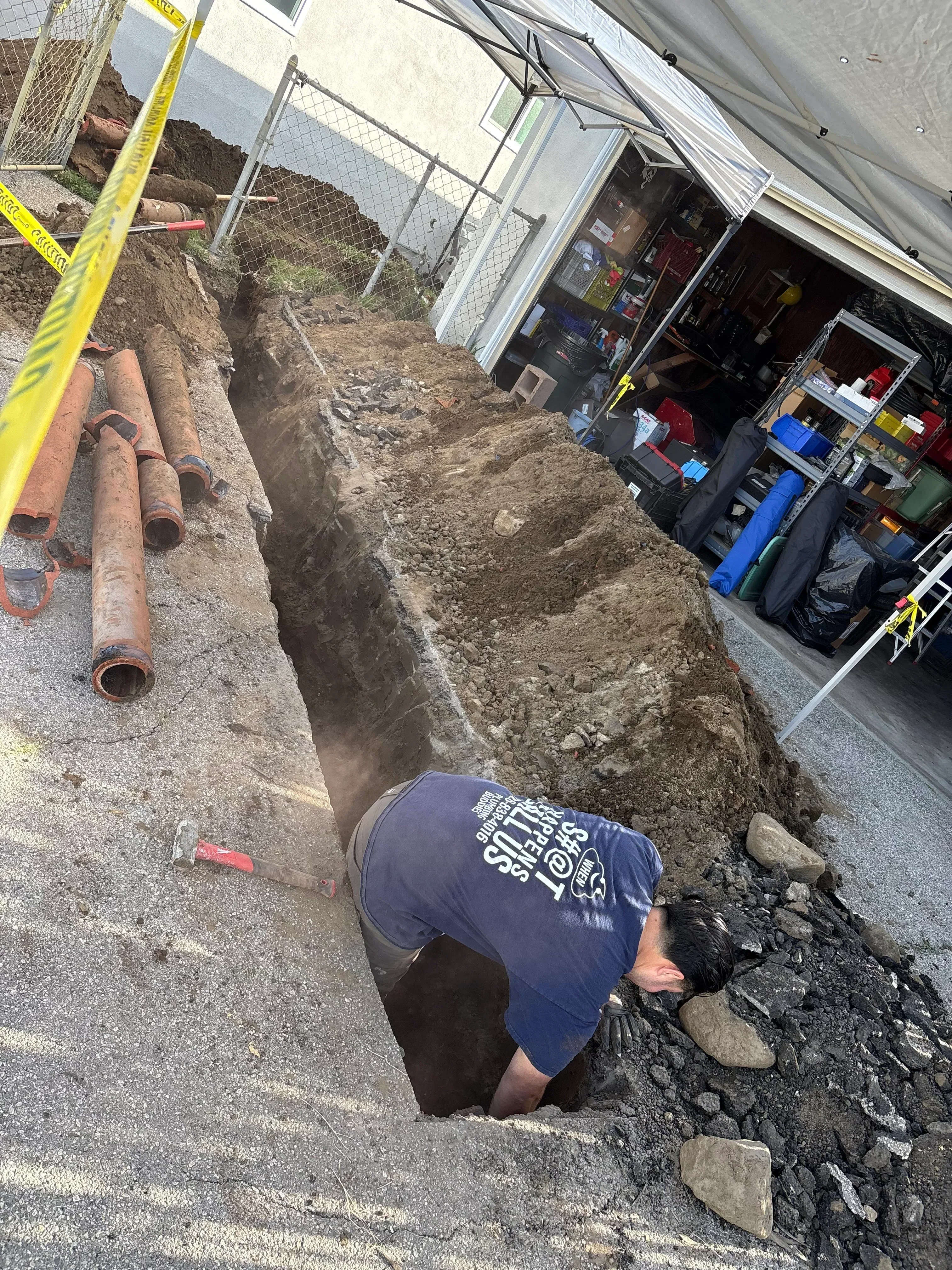 Excavated trench showing corroded cast iron sewer pipes during underground drainage system replacement